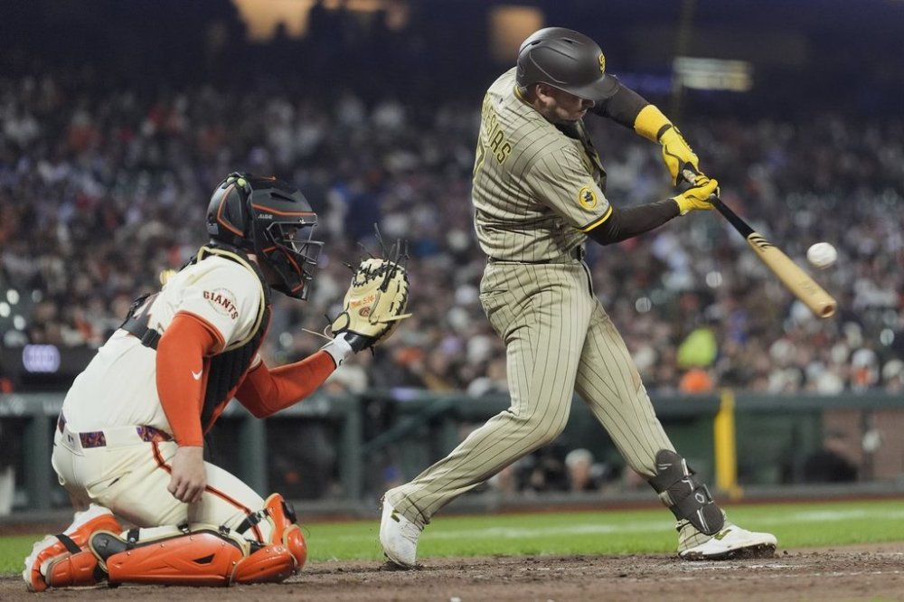 San Diego Padres' Jose Iglesias, right, hits a sacrifice fly next to San Francisco Giants catcher Patrick Bailey, left, that scored Jake Cronenworth during the tenth inning of a baseball game in San Francisco, Monday, June 2, 2025. (AP Photo/Jeff Chiu)