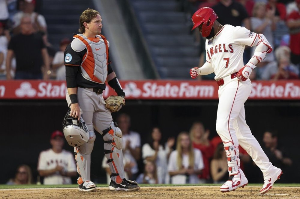 Los Angeles Angels' Jo Adell (7) reaches home plate after hitting a home run as Baltimore Orioles catcher Adley Rutschman, left, looks on during the fourth inning of a baseball game in Anaheim, Calif., Saturday, May 10, 2025. (AP Photo/Jessie Alcheh)
