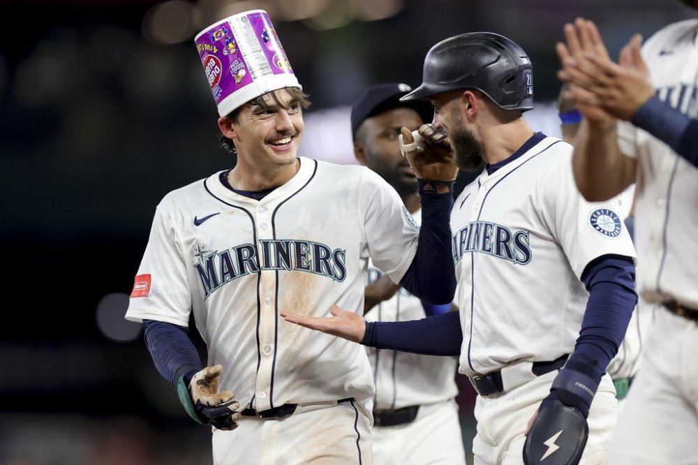 Seattle Mariners' Cole Young, left, celebrates with Miles Mastrobuoni, right, after reaching first base on a fielder's choice that allowed Mastrobuoni to score during the 11th inning of a baseball game against the Minnesota Twins, Saturday, May 31, 2025, in Seattle. (AP Photo/Ryan Sun)