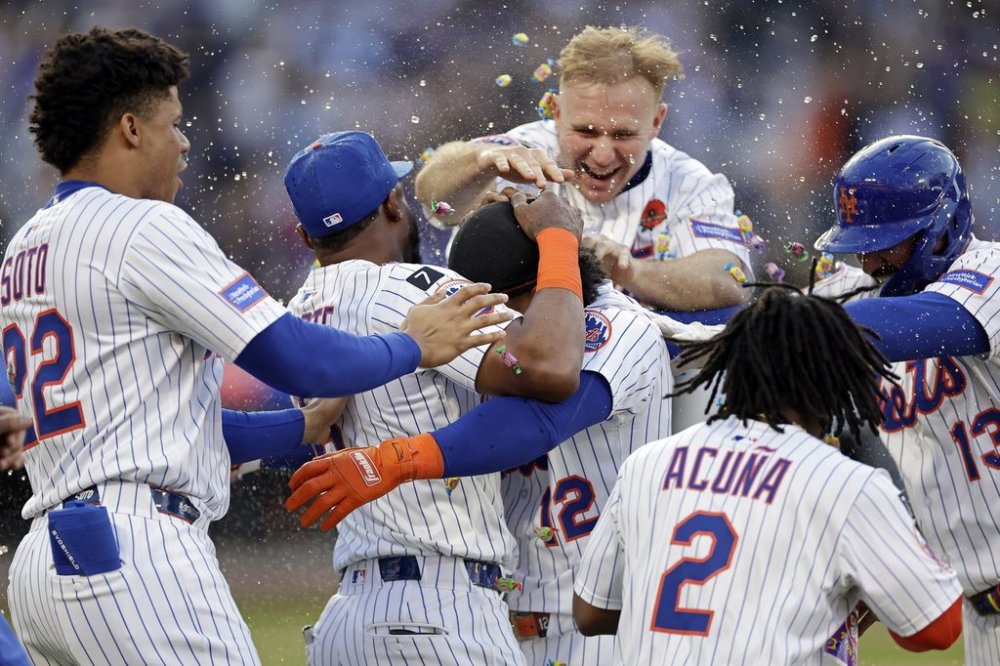 New York Mets' Francisco Lindor (12) is congratulated by teammates after hitting a walkoff sacrifice fly during the ninth inning of a baseball game against the Chicago White Sox, Monday, May 26, 2025, in New York. (AP Photo/Adam Hunger)