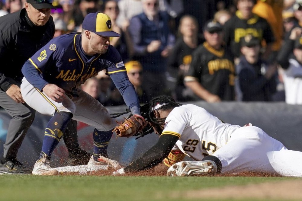 Pittsburgh Pirates' Oneil Cruz, right, slides safely into third base with an RBI triple as Milwaukee Brewers third baseman Caleb Durbin, left, apples a late tag during the seventh inning of a baseball game Saturday, May 24, 2025, in Pittsburgh. (AP Photo/Matt Freed)