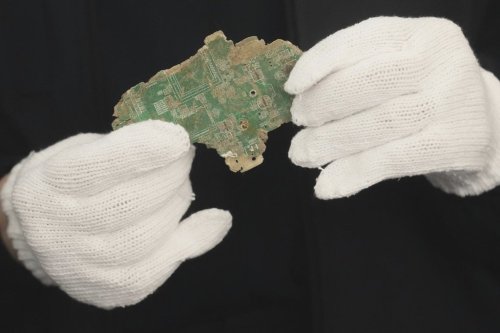 A Thai official shows a sample of illegally imported electronic waste from the United States which they said they seized at Bangkok Port during a press conference in Bangkok, Thailand, Wednesday, May 14, 2025. (AP Photo/Sakchai Lalit)
