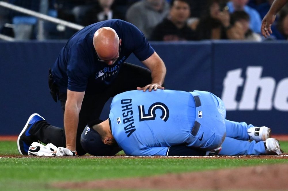 Blue Jays centre-fielder Daulton Varsho (5) is looked at by a team trainer after being injured while running the bases in the third inning of a Major League Baseball game in Toronto on Saturday, May 31, 2025. THE CANADIAN PRESS/Jon Blacker