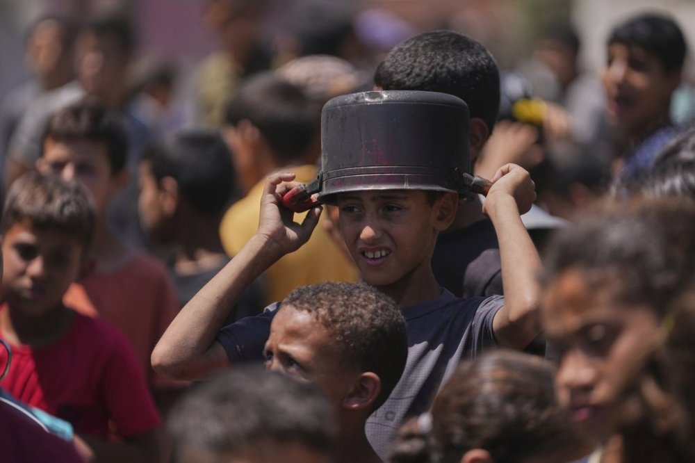 A young Palestinian waits to collect donated food at a food distribution kitchen in Deir al-Balah, Gaza Strip, Friday, May 30, 2025. (AP Photo/Abdel Kareem Hana)