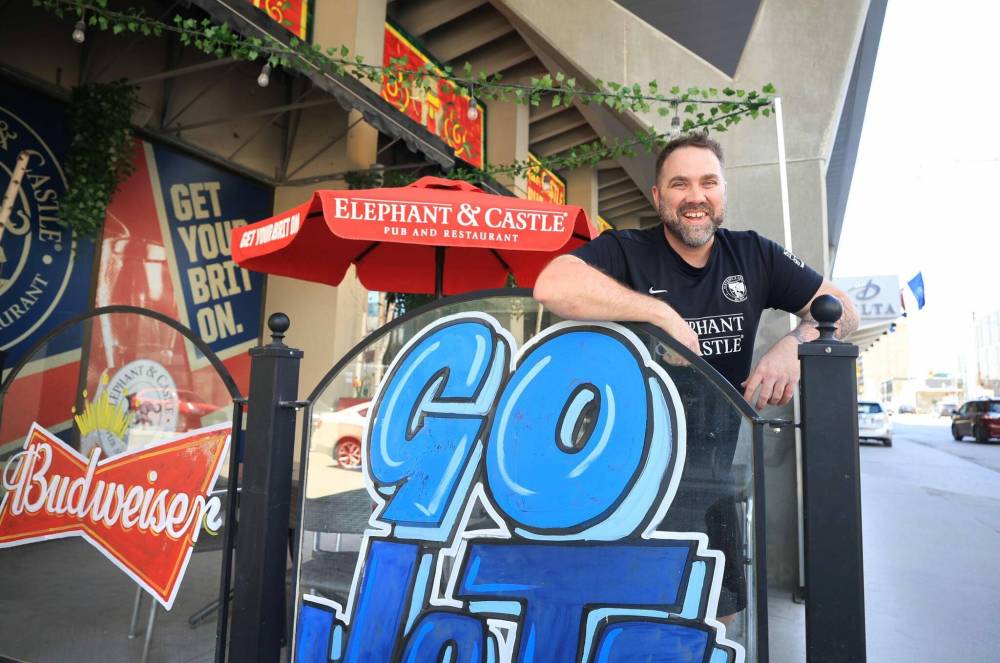 Ruth Bonneville / Free Press
                                Dwight Benson, general manager of Elephant and Castle on their outdoor patio, which is decorated to promote the Jets during their White-out street parties.