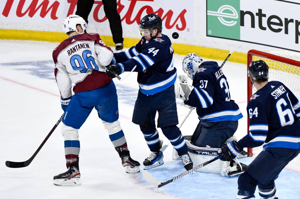 In Game 1 of a first-round playoff series in 2024 between the Winnipeg Jets and the Colorado Avalanche, goaltender Connor Hellebuyck (37) makes as save as teammate Josh Morrissey (44) checks Colorado Avalanche right wing Mikko Rantanen (96). (Fred Greenslade / The Canadian Press files)