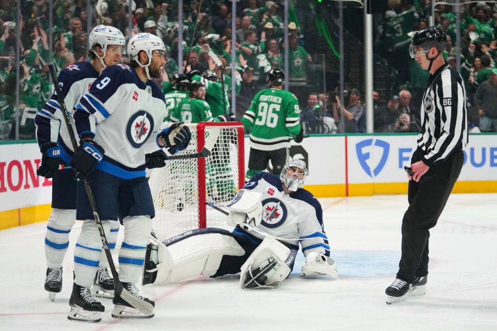 Julio Cortez / The Associated Press
Winnipeg Jets goaltender Connor Hellebuyck, bottom, Alex Iafallo (9) and Morgan Barron, left rear, talk with linesman Jesse Marquis (86) as the Dallas Stars celebrate a goal scored by Alexander Petrovic in the third period.