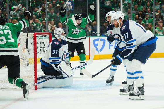 Winnipeg Jets’ Connor Hellebuyck and Adam Lowry react as the Dallas Stars players celebrate after scoring in Game 3 in Dallas, Sunday. (Julio Cortez / The Associated Press files)