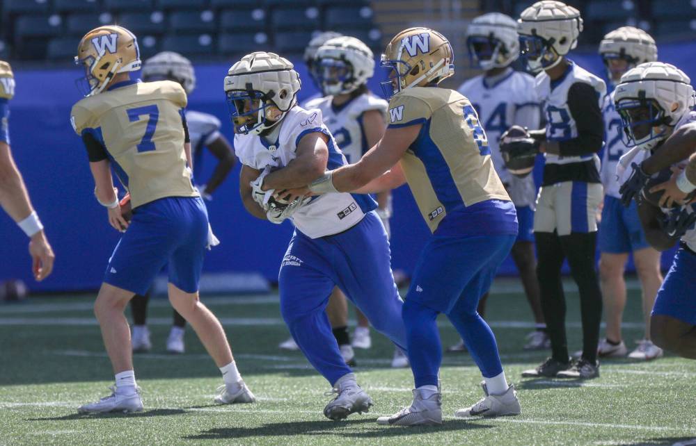 Ruth Bonneville / Free Press
Running back Matthew Peterson takes a hand off from quarterback Zach Collaros at Winnipeg Blue Bombers training camp Monday.