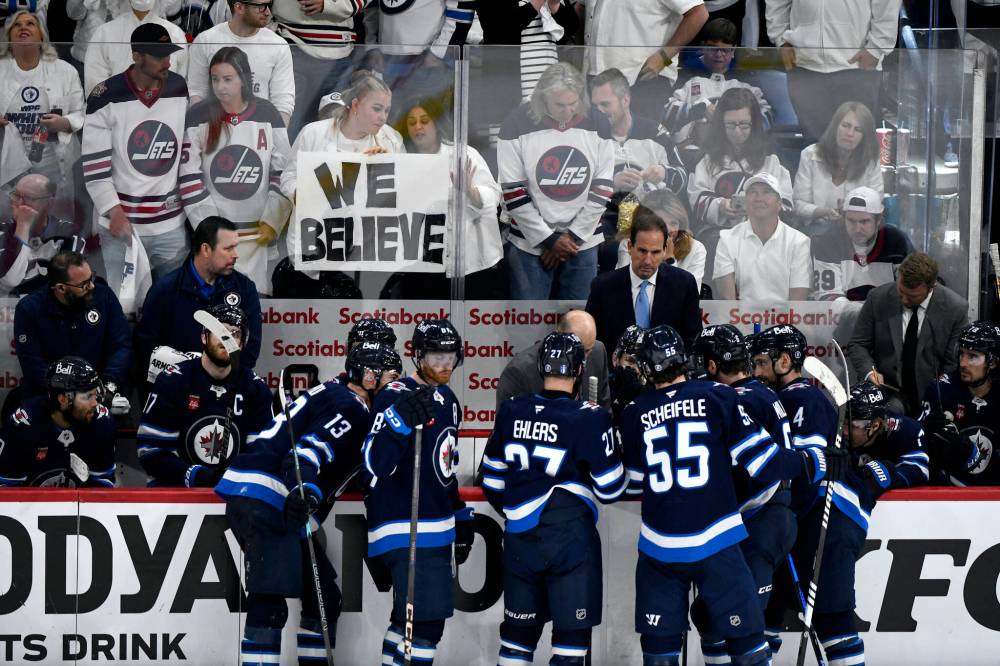 Winnipeg fans hold a sign that says “We Believe” on May 7 as Jets head coach Scott Arniel talks with players during a timeout against the Dallas Stars. (Fred Greenslade / The Canadian Press files)