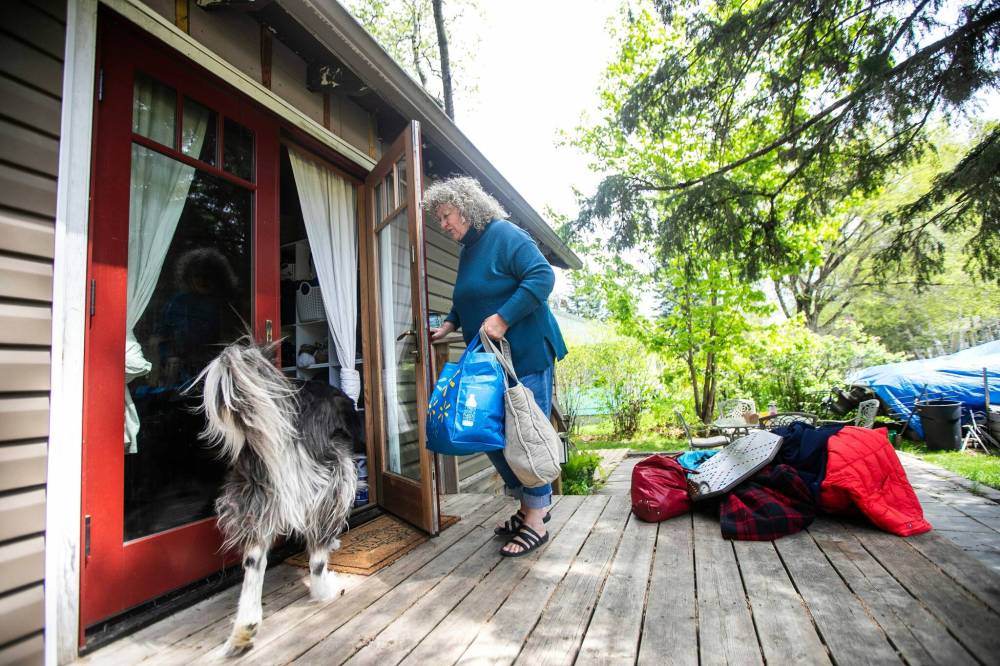 MIKAELA MACKENZIE / FREE PRESS
Falcon Lake resident Audrey Hill (with dog Atticus) unloads the car after returning following the wildfire evacuation order.