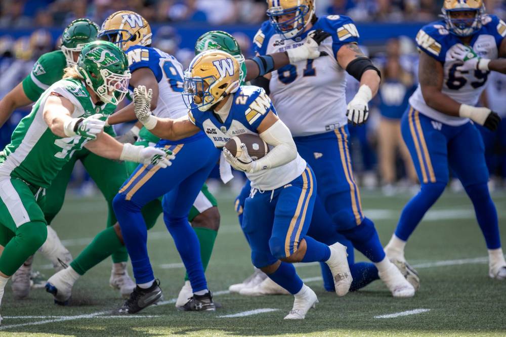 BROOK JONES/FREE PRESS Winnipeg Blue Bombers running back Matthew Peterson (No. 22) runs with the football while Riders defensive lineman Lake Korte-Moore (No. 49) prepares to tackle him during second quarter action Saturday.
