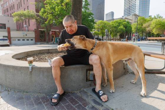 Vinny Hall and his dog, Baby, enjoy a moment together with the free egg sandwich in Old Market Square Thursday morning. (Mike Deal / Free Press)