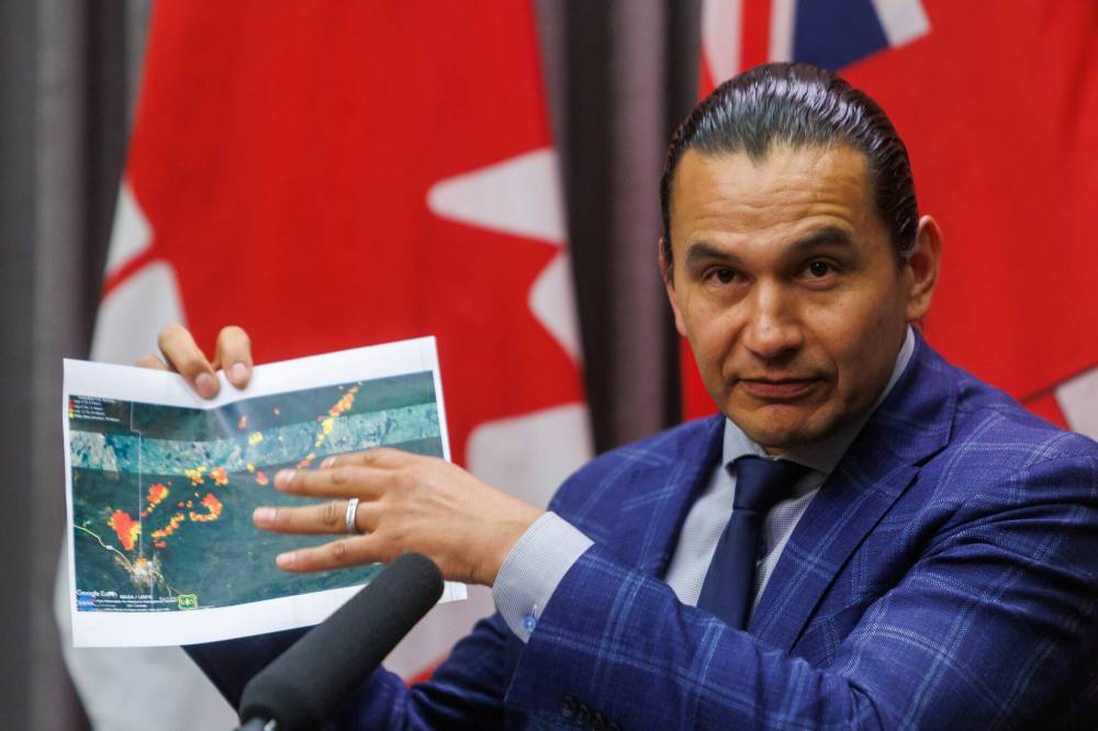 MIKE DEAL / FREE PRESS
                                Premier Wab Kinew holds up a satellite image of Flin Flon that shows where the wildfires are during an update held at the Manitoba Legislative building Friday afternoon.