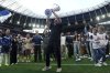 Tottenham Hotspur manager Ange Postecoglou holds up the Europa League trophy on the pitch during the English Premier League soccer match between Tottenham Hotspur and Brighton and Hove Albion at the Tottenham Hotspur Stadium, London. Picture date: Sunday May 25, 2025. (John Walton/PA via AP)