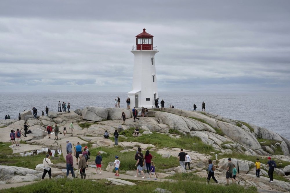 Hundreds of people walk near the lighthouse in Peggy's Cove, N.S., Tuesday, July 4, 2023. THE CANADIAN PRESS/Darren Calabrese