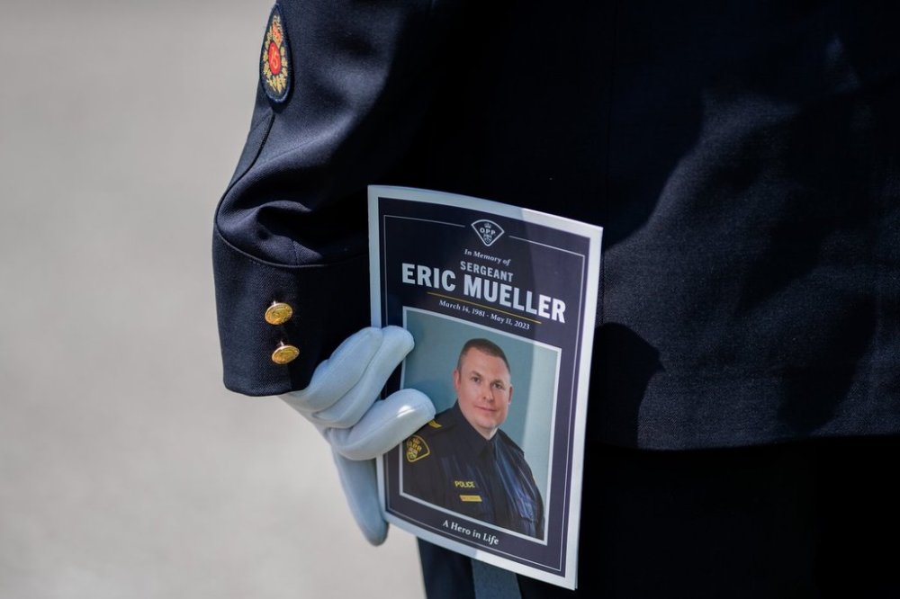 A member of the Ontario Provincial Police holds a program during the funeral of Ontario Provincial Police Sgt. Eric Mueller in Ottawa, on Thursday, May 18, 2023. THE CANADIAN PRESS/Spencer Colby