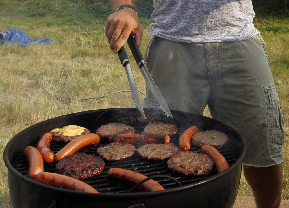 FILE - A man grills hamburgers and hot dogs in Arlington, Va., July 4, 2012. (AP Photo/Alex Brandon, File)