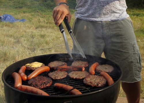 FILE - A man grills hamburgers and hot dogs in Arlington, Va., July 4, 2012. (AP Photo/Alex Brandon, File)