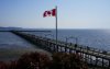 A Canada flag blows as people visit the White Rock Pier in White Rock, B.C., on Wednesday, April 23, 2025. The United States is seen in the distance. THE CANADIAN PRESS/Sean Kilpatrick