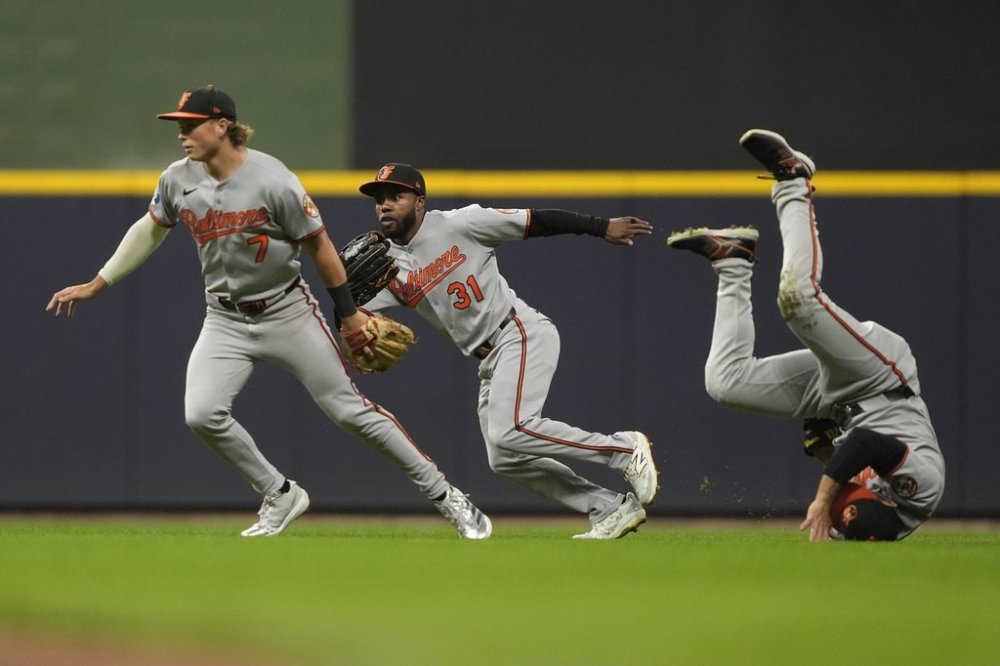 Baltimore Orioles' Jackson Holliday (7), Cedric Mullins (31), and Ramón Laureano, right, are unable to reach a fly ball during the fourth inning of a baseball game against the Milwaukee Brewers, Tuesday, May 20, 2025, in Milwaukee. (AP Photo/Aaron Gash)