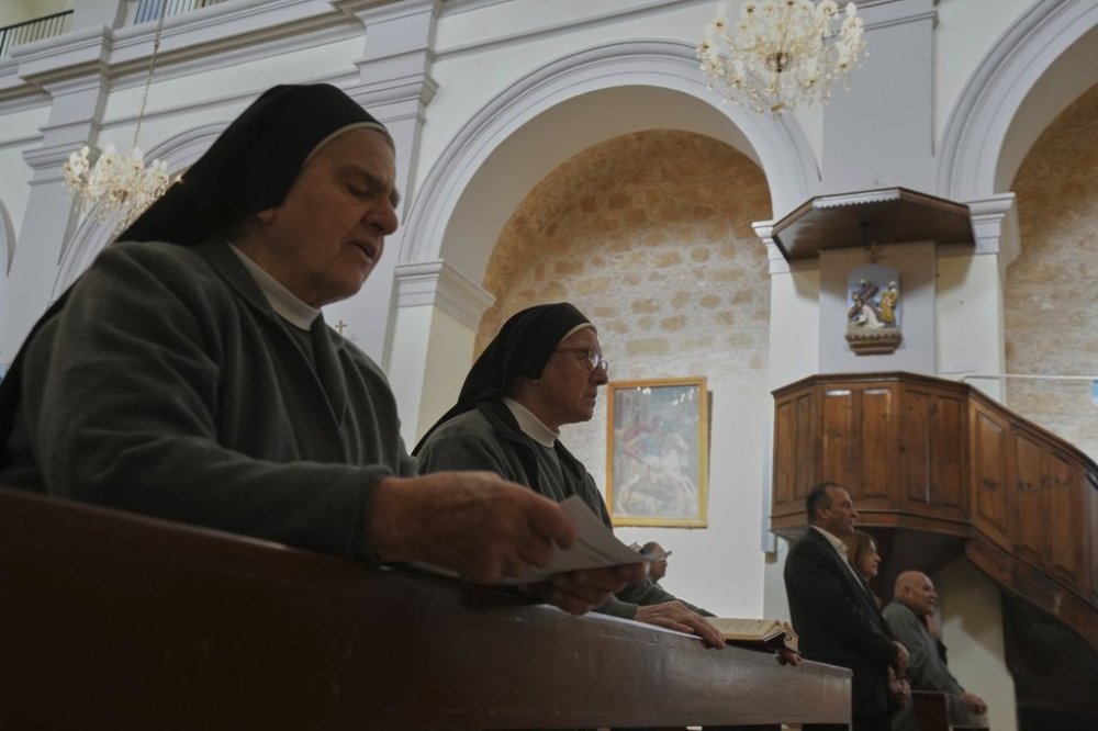 Maronite Catholic nuns recite hymns during a service in outside St. George Church in the Maronite village of Kormakitis in the breakaway north of the ethnically divided Cyprus on Wednesday, April 23, 2025. (AP Photo/Petros Karadjias)