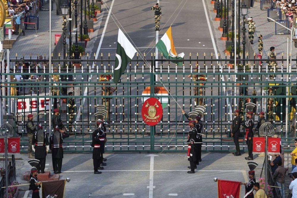 Pakistan's Rangers soldiers, in black, and Indian Border Security Forces soldiers, behind the gate, lower their flags during a daily closing ceremony at the Wagah, a joint post on the Pakistan and India border, near Lahore, Pakistan, Monday, May 5, 2025. (AP Photo/K.M. Chaudary)