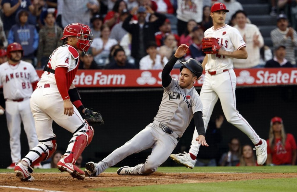 New York Yankees' Cody Bellinger, center, slides to score with Los Angeles Angels catcher Logan O'Hoppe, front left, at home plate on a three-run double by teammate Anthony Volpe during the fourth inning of a baseball game Monday, May 26, 2025, in Anaheim, Calif. (AP Photo/Kevork Djansezian)
