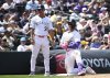 Colorado Rockies third base coach Warren Schaeffer, left, and designated hitter Hunter Goodman (15) look on after Goodman's triple in the third inning of a baseball game against the San Diego Padres, Sunday, May 11, 2025, in Denver. After the game, Schaeffer was named interim manager of the Rockies. (AP Photo/Geneva Heffernan)