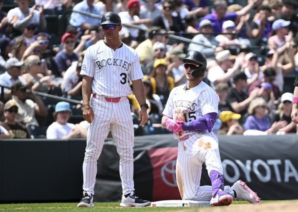 Colorado Rockies third base coach Warren Schaeffer, left, and designated hitter Hunter Goodman (15) look on after Goodman's triple in the third inning of a baseball game against the San Diego Padres, Sunday, May 11, 2025, in Denver. After the game, Schaeffer was named interim manager of the Rockies. (AP Photo/Geneva Heffernan)