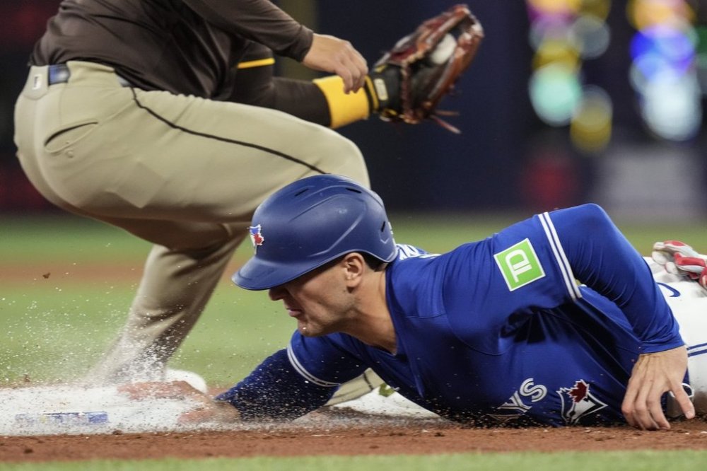 Toronto Blue Jays' Daulton Varsho (5) safely dives back into third base during first inning MLB baseball action against the San Diego Padres in Toronto on Thursday, May 22, 2025. THE CANADIAN PRESS/Chris Young