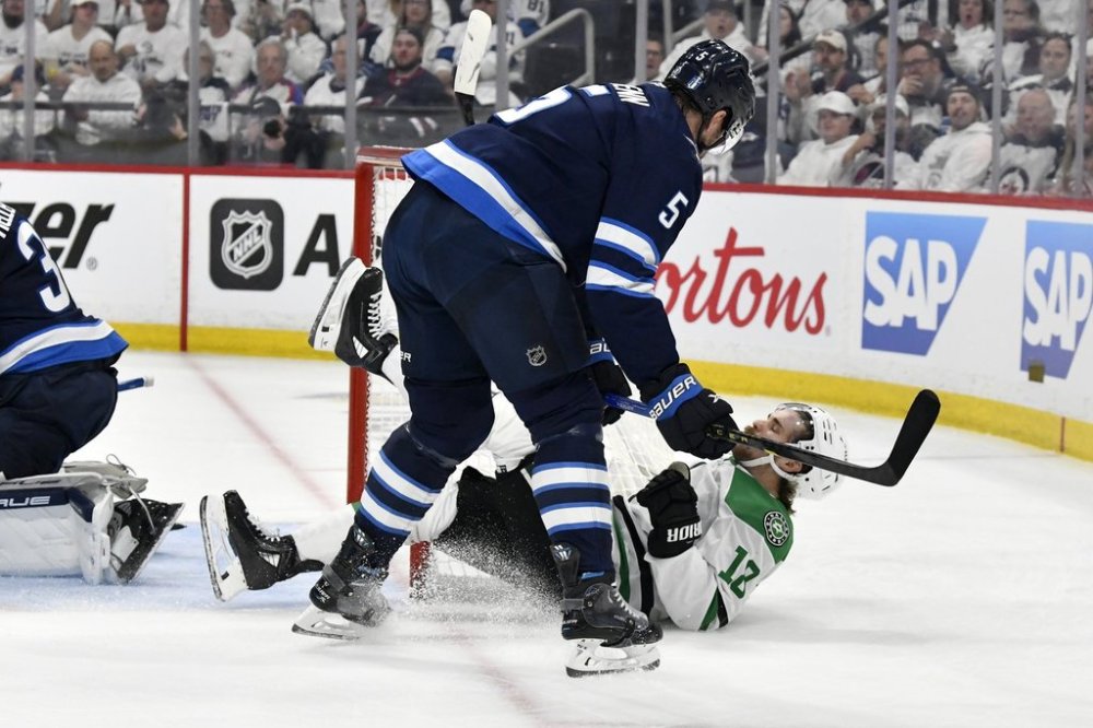 Dallas Stars' Sam Steel (18) is checked to the ice by Winnipeg Jets' Luke Schenn (5) during first period NHL playoff hockey action in Winnipeg, Thursday, May 15, 2025. THE CANADIAN PRESS/Fred Greenslade