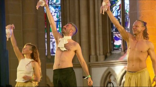 This grab taken from video shows performers dancing as they hold raw, plucked chickens wrapped in diapers, inside Paderborn's cathedral, Germany, Friday May 16, 2025. (RTL via AP)