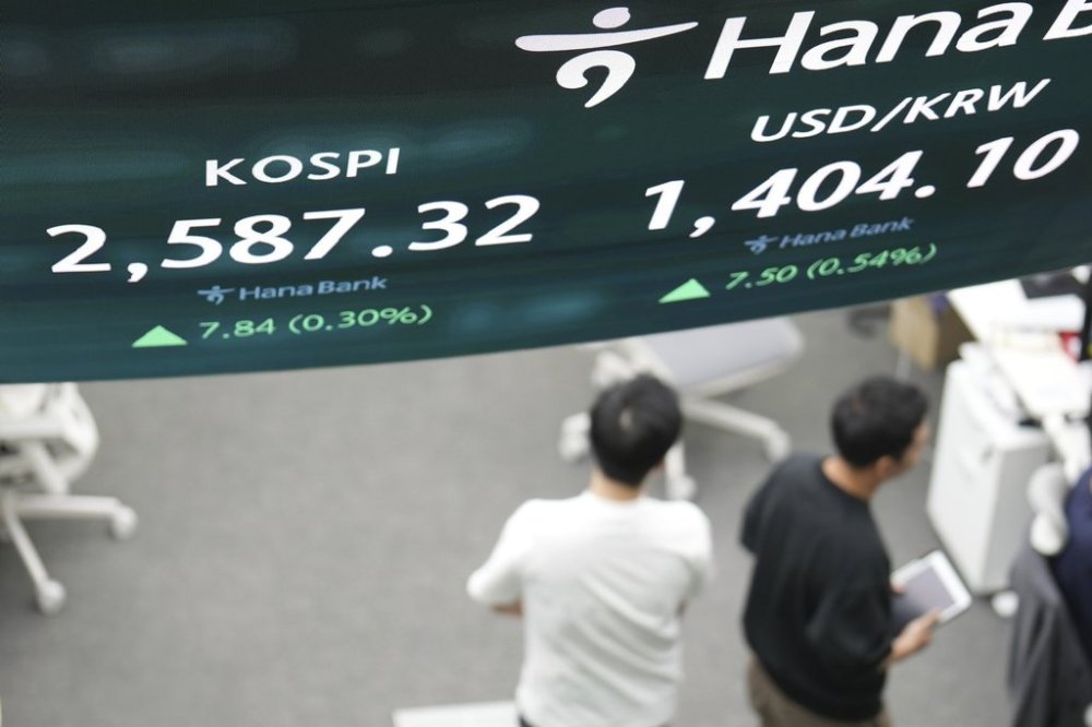 Dealers walk past near the screens showing the Korea Composite Stock Price Index (KOSPI), left, and the foreign exchange rate between U.S. dollar and South Korean won at a dealing room of Hana Bank in Seoul, South Korea, Friday, May 9, 2025. (AP Photo/Lee Jin-man)