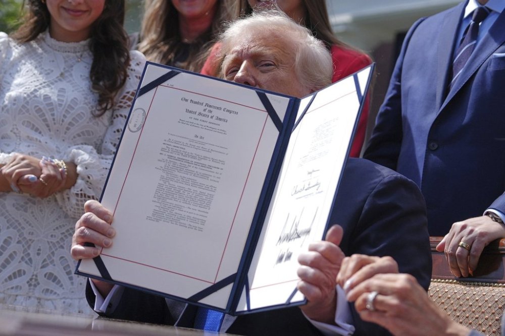 President Donald Trump holds up a bill for the
