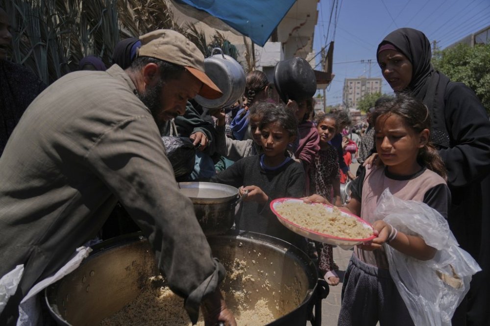 Palestinian children get food at a food distribution kitchen in Deir al-Balah, Gaza Strip, Friday, May 30, 2025. (AP Photo/Abdel Kareem Hana)