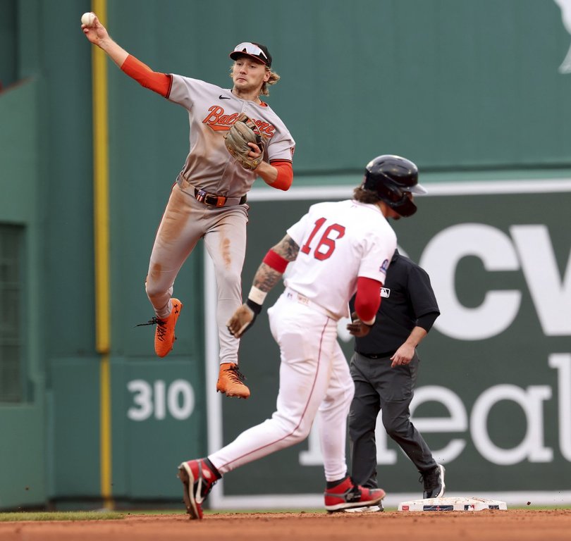 Baltimore Orioles shortstop Gunnar Henderson, left, throws to first base after tagging out Boston Red Sox's Jarren Duran (16) at second base on a double play during the fifth inning of a baseball game Sunday, May 25, 2025, in Boston. (AP Photo/Mark Stockwell)