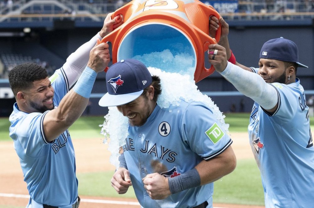 Toronto Blue Jays Addison Barger, centre, is doused by teammates Janatan Clase, left and Vladimir Guerrero Jr to celebrate their team's defeat of the Athletics in MLB baseball action in Toronto on Sunday, June 1, 2025. THE CANADIAN PRESS/Jon Blacker