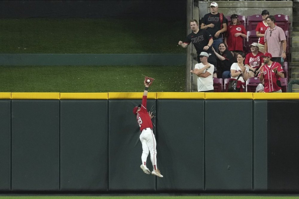 Cincinnati Reds' TJ Friedl catches a fly ball at the wall to end the game in the ninth inning of a baseball game against the Milwaukee Brewers, Tuesday, June 3, 2025, in Cincinnati. (AP Photo/Kareem Elgazzar)