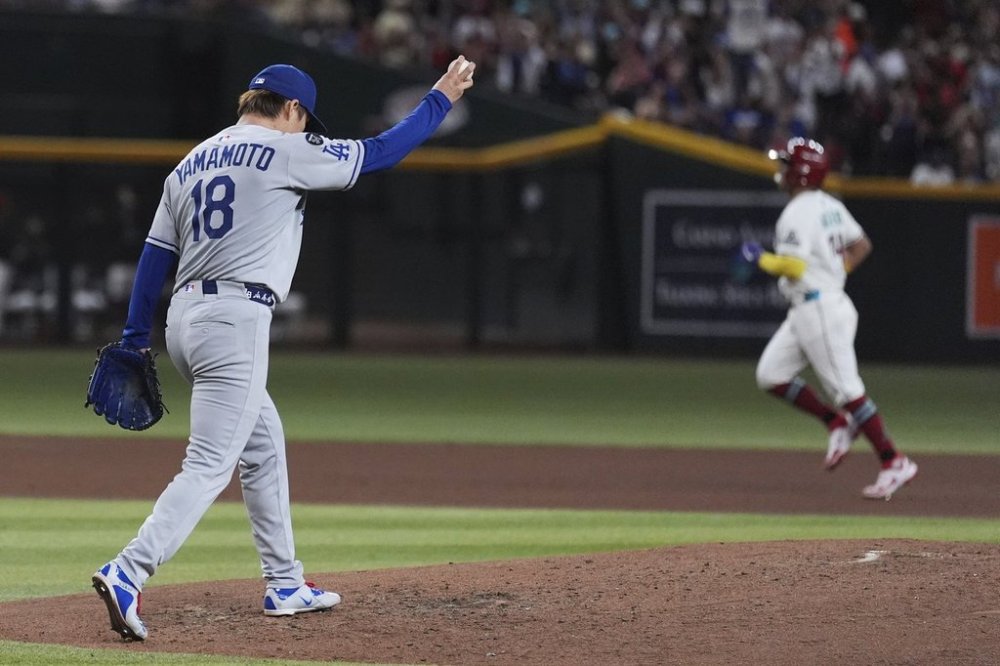 Los Angeles Dodgers starting pitcher Yoshinobu Yamamoto (18), of Japan, holds a new ball after giving up a grand slam to Arizona Diamondbacks' Gabriel Moreno, right, during the fourth inning of a baseball game Thursday, May 8, 2025, in Phoenix. (AP Photo/Ross D. Franklin)