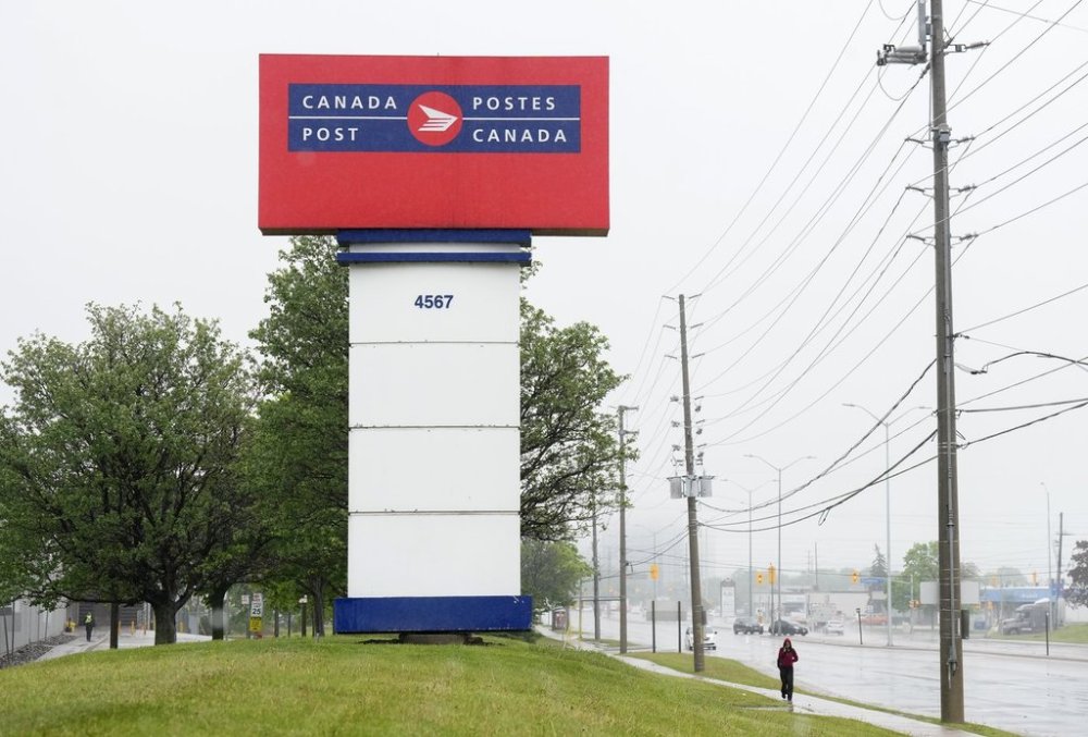 People walk past the Canada Post facility in Mississauga, Ont., on Thursday, May 22, 2025. Canada Post is set to meet with the postal workers' union on Sunday, May 25, 2025. THE CANADIAN PRESS/Nathan Denette