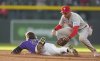 Colorado Rockies' Jordan Beck, left, slides safely into second base with a double as Philadelphia Phillies shortstop Trea Turner, right, applies a late tag in the third inning of a baseball game Monday, May 19, 2025, in Denver. (AP Photo/David Zalubowski)