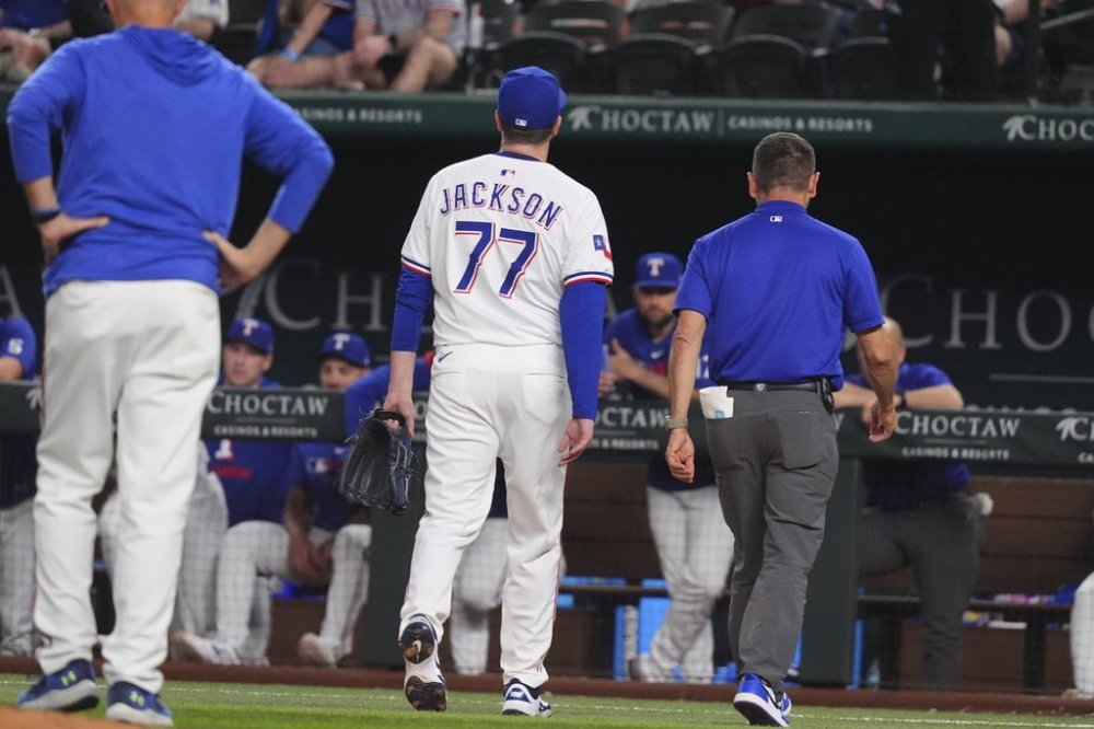 Texas Rangers pitcher Luke Jackson (77) leaves after getting hit by a line drive during the ninth inning of a baseball game against the Colorado Rockies, Monday, May 12, 2025, in Arlington, Texas. (AP Photo/LM Otero)
