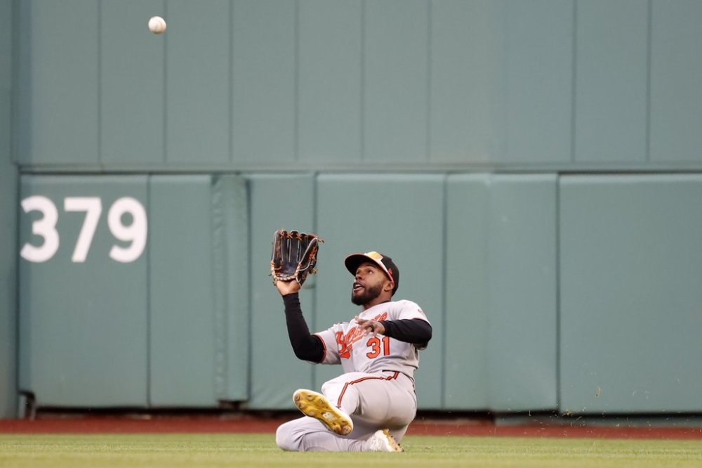 Baltimore Orioles center fielder Cedric Mullins slides to catch a fly ball hit by Boston Red Sox's Ceddanne Rafaela during the seventh inning of the first baseball game of a doubleheader, Saturday, May 24, 2025, at Fenway Park in Boston. (AP Photo/Mary Schwalm)