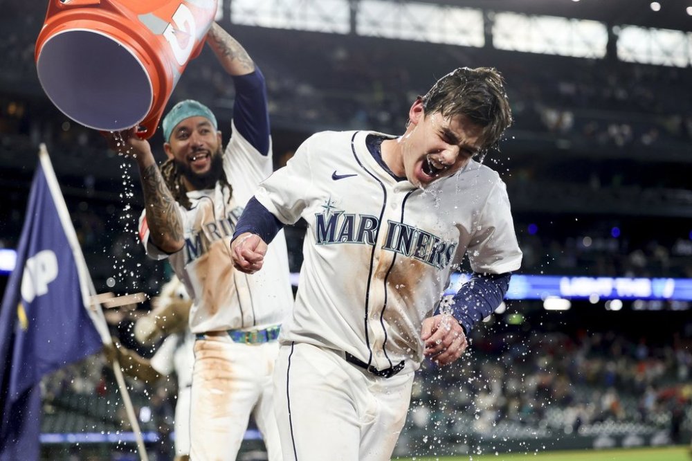 Seattle Mariners' Cole Young is dunked with water by J.P. Crawford after reaching first on a fielder's choice that allowed Miles Mastrobuoni to score the walk-off run during the 11th inning of a baseball game against the Minnesota Twins Saturday, May 31, 2025, in Seattle. (AP Photo/Ryan Sun)