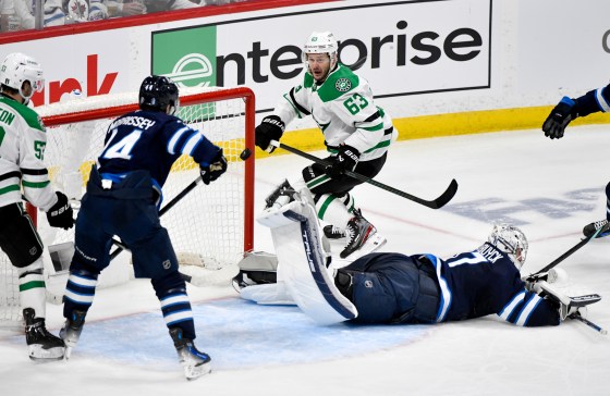 Jets goalie Connor Hellebuyck (37) gets a piece of the puck to deflect the shot from Dallas Stars' Evgenii Dadonov (63) in the second period of Friday's game.(Fred Greenslade / The Canadian Press files)