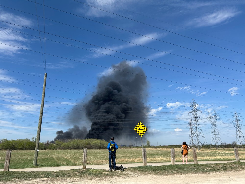 ERIK PINDERA / FREE PRESSPassersby at the end of Wabasha Street watch plumes of smoke from a massive fire in north Transcona on Monday afternoon.