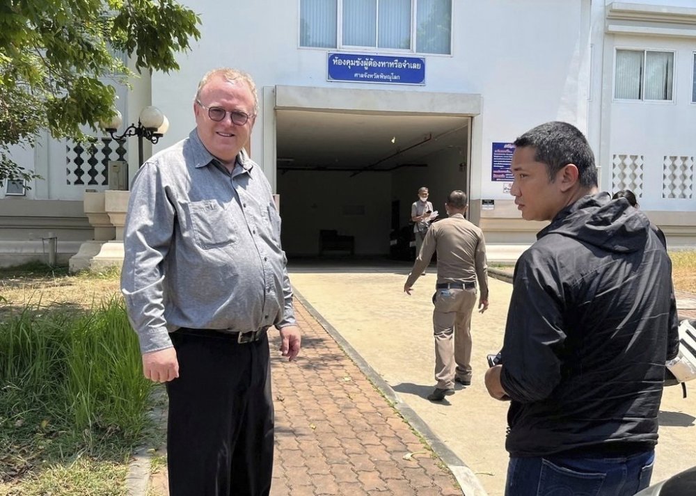 FILE - U.S. political science lecturer Paul Chambers, left, of Thailand's Naresuan University, stands outside the police station in Phitsanulok, Thailand, where he was arrested on charges of insulting the monarchy. (AP Photo, file)