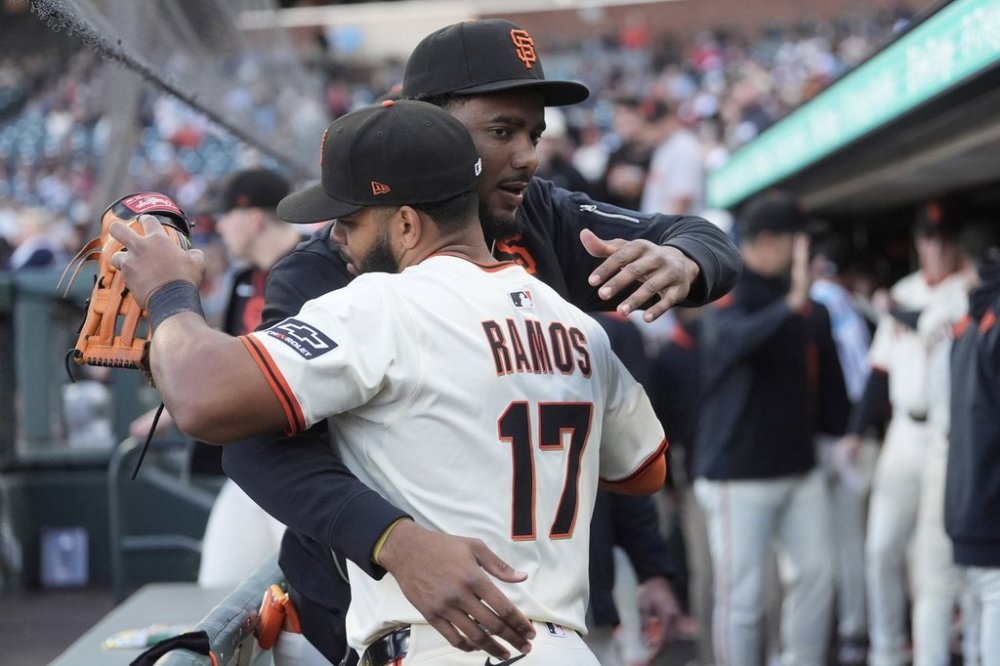 San Francisco Giants' Heliot Ramos (17) hugs Jerar Encarnacion in the dugout before a baseball game against the San Diego Padres in San Francisco, Monday, June 2, 2025. (AP Photo/Jeff Chiu)