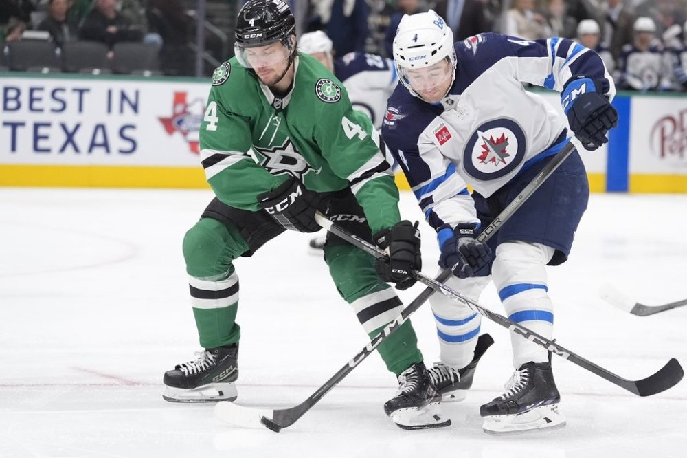Dallas Stars defenceman Miro Heiskanen, left, and Winnipeg Jets defenceman Neal Pionk, right, try to control the puck during the second period of an NHL game on Sunday, Dec. 1, 2024, in Dallas. (AP Photo/LM Otero)